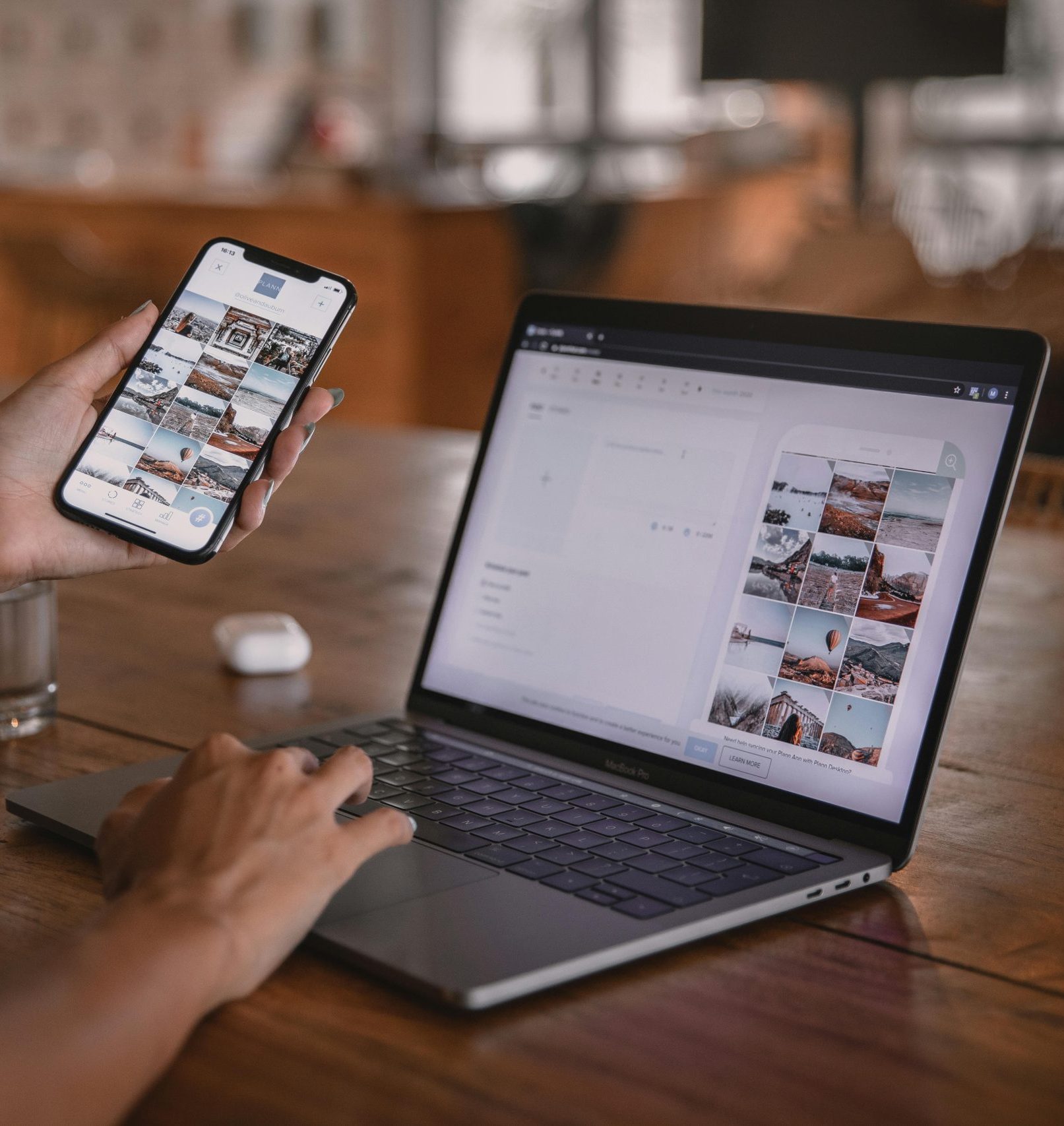 Woman holding cell phone and working on laptop.